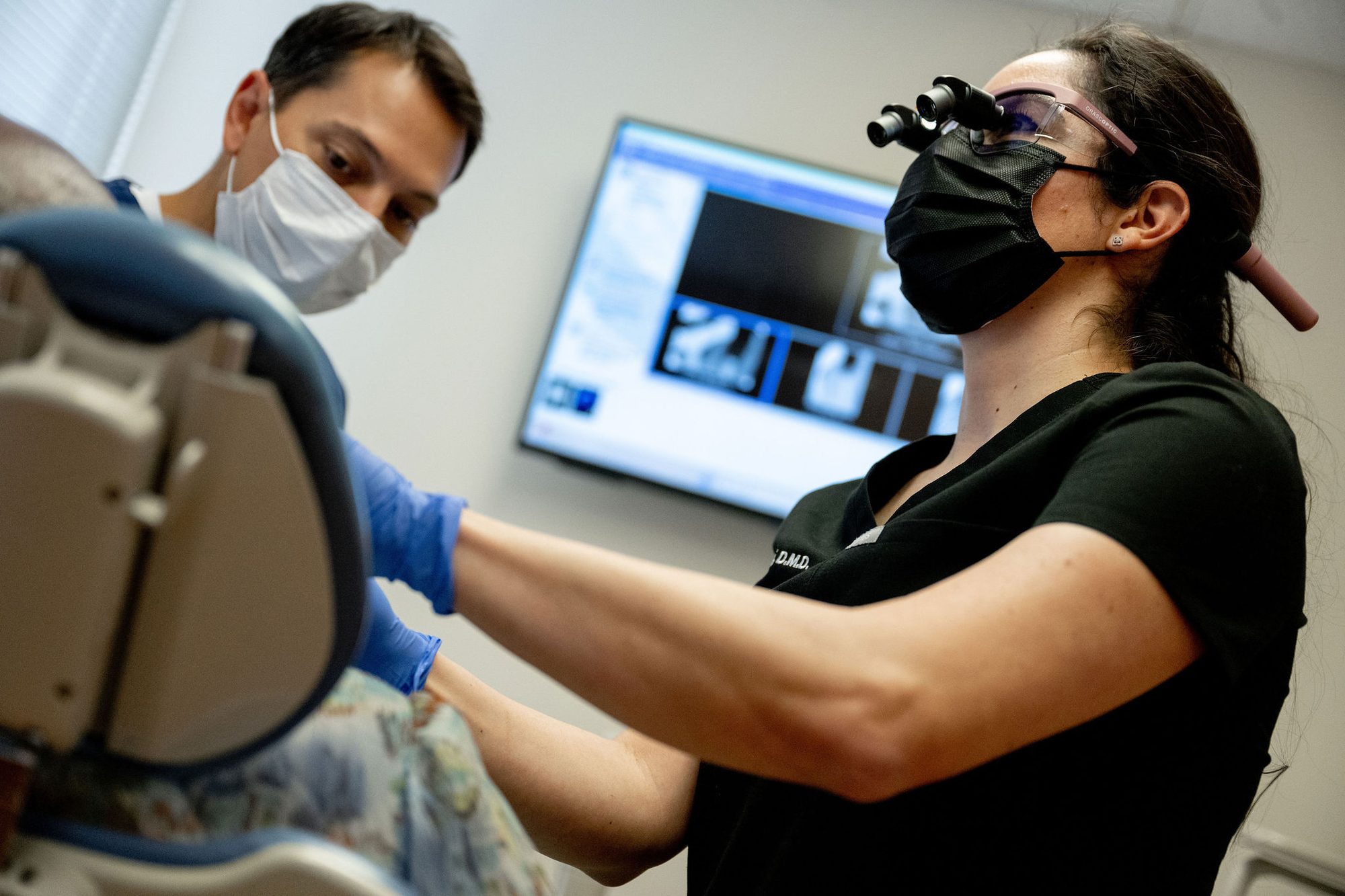Doctor and assistant performing cosmetic procedure with loupes