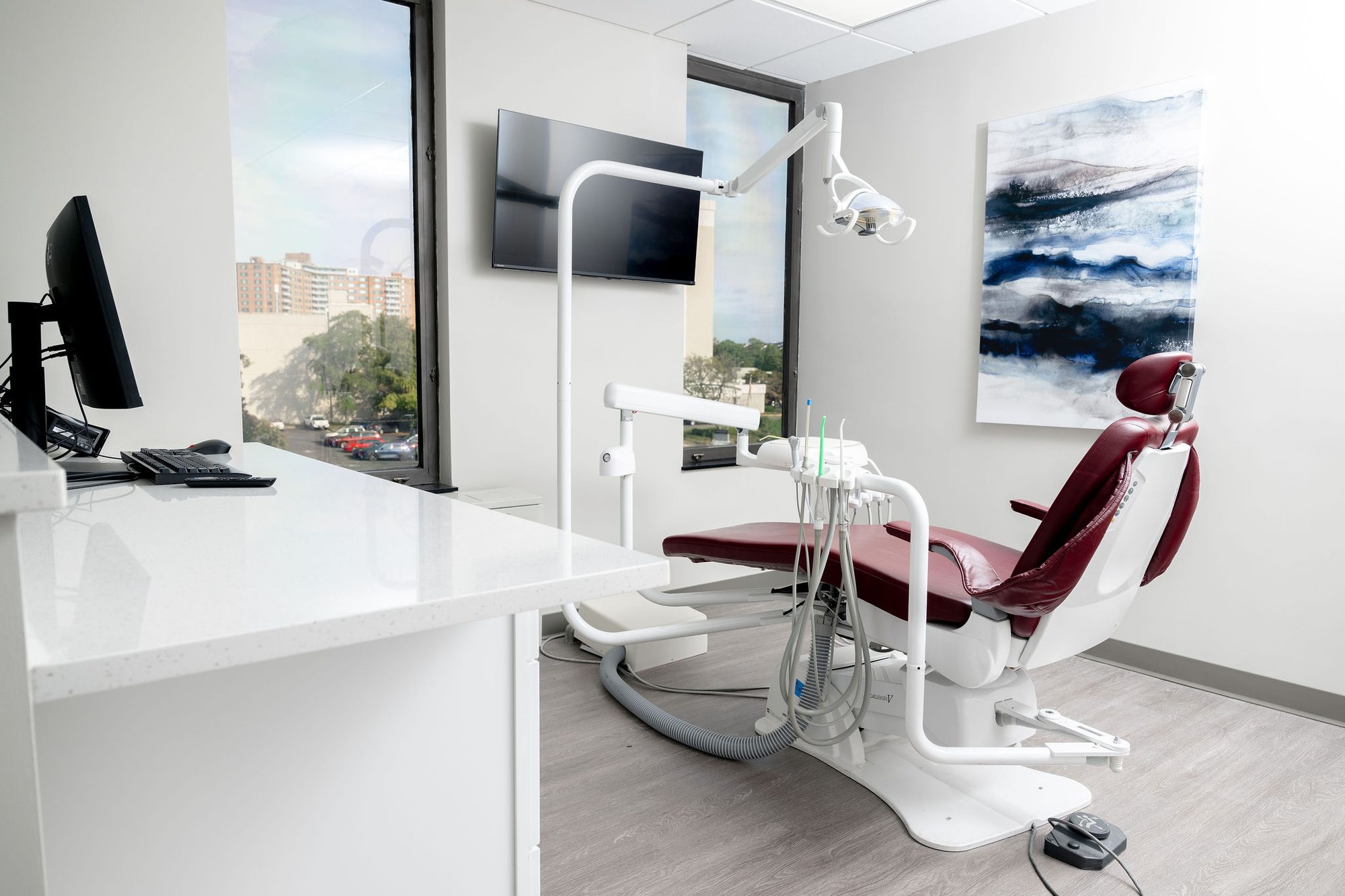 Operatory with watercolor art, city views, and burgundy dental chair